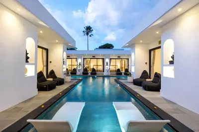 an indoor swimming pool with chairs and a pool house at Villa Kelolyne in Seminyak