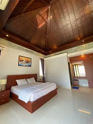 a bedroom with a large bed with a wooden ceiling at Villa Granatlia in Sanur