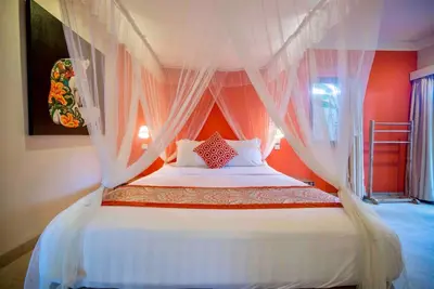 a bedroom with a canopy bed with white curtains at Villa Kuda Sumba Umalas - Seminyak Area in Kerobokan
