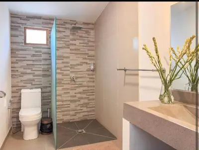 a bathroom with a toilet and a glass shower stall at Villa Dekat Pantai Batu Belig in Canggu