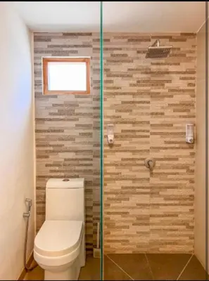 a bathroom with a toilet and a glass shower at Villa Dekat Pantai Batu Belig in Canggu