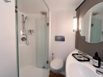 a bathroom with a shower and a toilet and a sink at Luminor Hotel Legian Seminyak - Bali in Legian