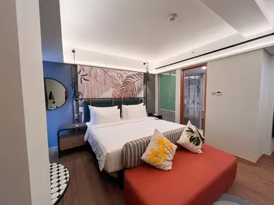 a bedroom with a large bed and a red bench at Luminor Hotel Legian Seminyak - Bali in Legian