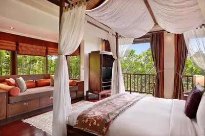a bedroom with a canopy bed and a couch at Barimantra 4BR Trees View Pool Villa CYN in Jimbaran