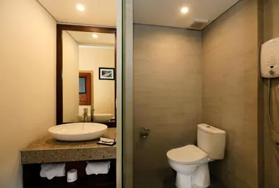 a bathroom with a toilet and a sink and a mirror at Kutabex Beachfront Hotel in Kuta