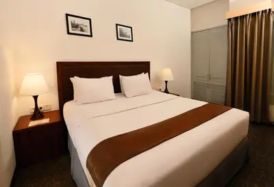 a large bed in a hotel room with two lamps at Kutabex Beachfront Hotel in Kuta
