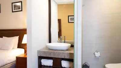a bathroom with a sink on a counter with a bed at Kutabex Beachfront Hotel in Kuta