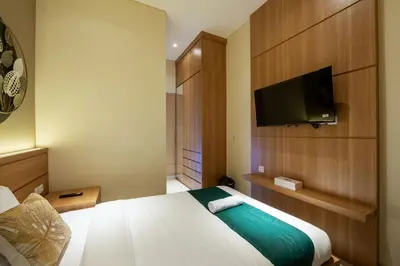 a hotel room with a bed and a flat screen tv at Cove Tripuri House Bali in Denpasar