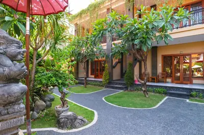 a courtyard of a building with trees and an umbrella at Gora Beach Inn in Kuta