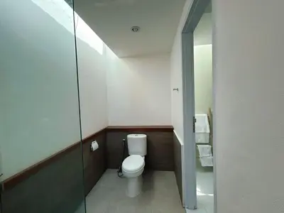 a small bathroom with a toilet and a glass door at Astana Villas in Seminyak