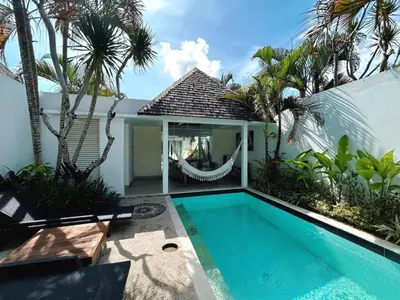 a villa with a swimming pool and palm trees at Astana Villas in Seminyak