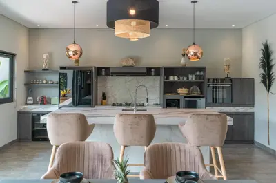 a kitchen with a large island with bar stools at Villa Koya : Luxurious and Modern 3BR Villa in Seminyak! in Seminyak
