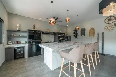 a kitchen with a large white island with bar stools at Villa Koya : Luxurious and Modern 3BR Villa in Seminyak! in Seminyak