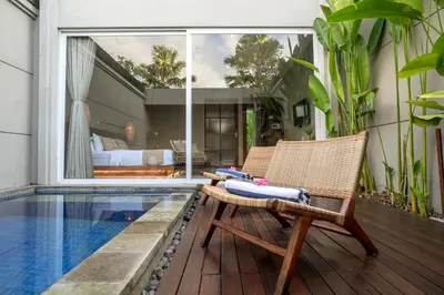 a chair sitting on a deck next to a swimming pool at Damarya Villa Canggu in Canggu
