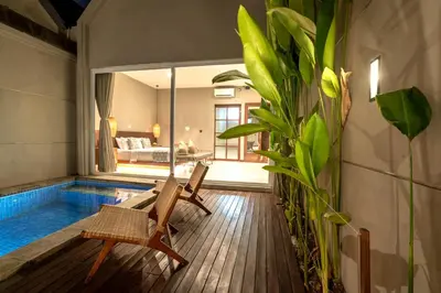 a room with a swimming pool and two chairs and a house at Damarya Villa Canggu in Canggu
