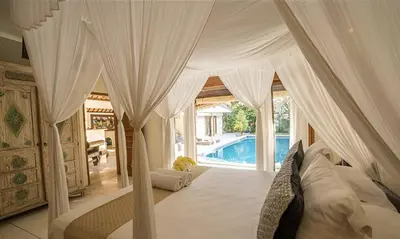 a bedroom with a white canopy bed and a pool at Villa Umah Maya 3BR Seminyak in Seminyak
