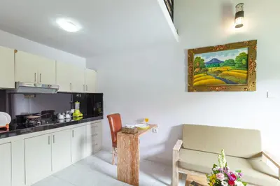 a kitchen with white cabinets and a painting on the wall at Maisaba Seminyak Loft & Villas in Seminyak