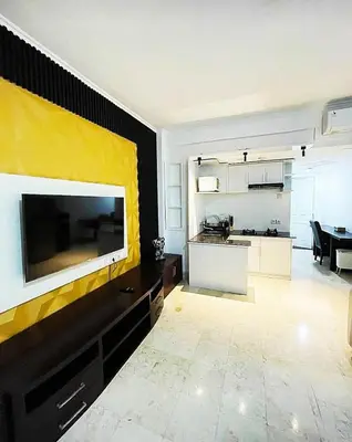 a living room with a large tv on a wall at Suite Hotel Apartment Legian by RCP in Seminyak