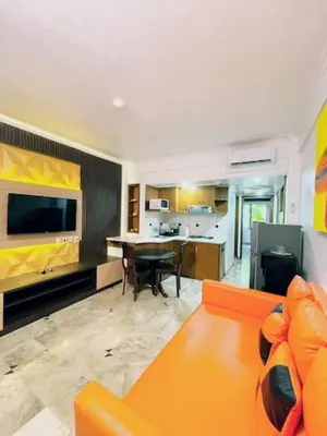 a living room with an orange couch and a table at Suite Hotel Apartment Legian by RCP in Seminyak