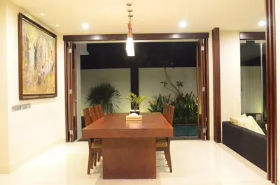 a dining room with a table and a couch at The Arnaya in Kuta