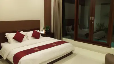 a bedroom with a large bed with red pillows at The Arnaya in Kuta