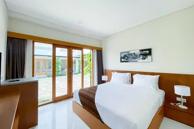 a bedroom with a white bed and a television at Aldan Guest House Syariah in Pesanggaran