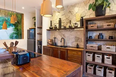 a kitchen with a wooden counter top and a stone wall at Villa Senya - Bali Bliss 3BR Mediterranean Escape with Private Pool, Stylish Retreat Between Seminyak & Canggu in Kerobokan