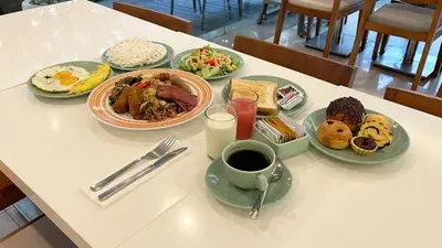 a table with plates of food and a cup of coffee at Kuta Galleria Hotel in Kuta