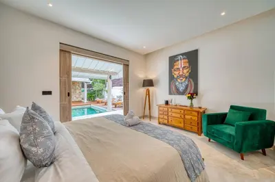 a bedroom with a large bed and a green chair at Beautiful villa Yang Tao in the heart of Seminyak with private staff in Seminyak