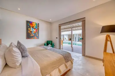a bedroom with a large bed with a painting on the wall at Beautiful villa Yang Tao in the heart of Seminyak with private staff in Seminyak