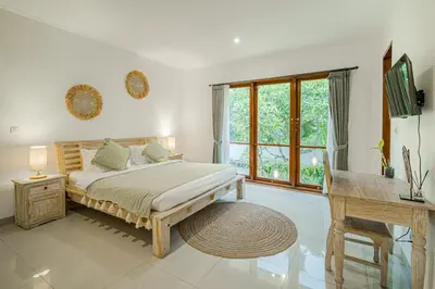 a bedroom with a bed and a desk and a window at Villa Miamara by Bali Villa Solutions in Seminyak