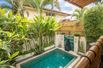 a swimming pool in a garden with a fence and trees at Villa Seriska Seminyak, 5-Star Private Pool Villa, Walk to Dining & Shopping in Seminyak