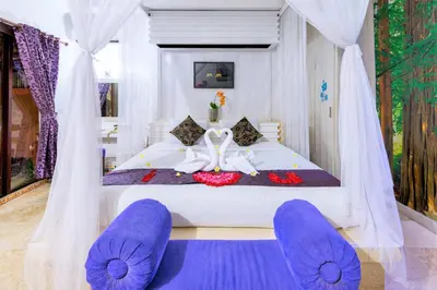 a bedroom with a large white bed with purple cushions at Romantic Private Villas Kuta Bali in Kuta