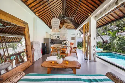 a living room with a table and a swimming pool at Villa Anouk in Seminyak