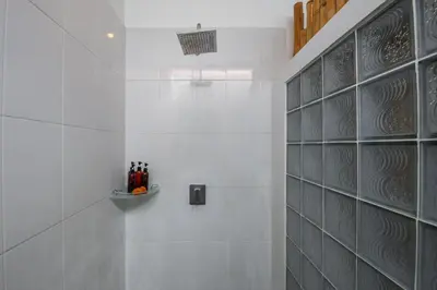 a white tiled bathroom with a glass wall at Villa Anouk in Seminyak