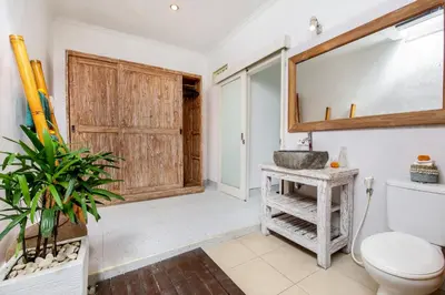 a bathroom with a toilet and a wooden door at Villa Anouk in Seminyak