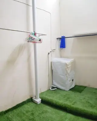 a white room with a green floor and a pole at Laura Dewi House in Jimbaran
