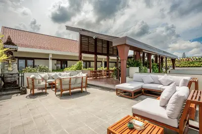 a patio with white couches and a table and chairs at Sedasa Lodge in Canggu
