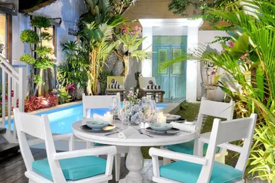 a table and chairs in a patio with a pool at Selasih Beach House in Seminyak