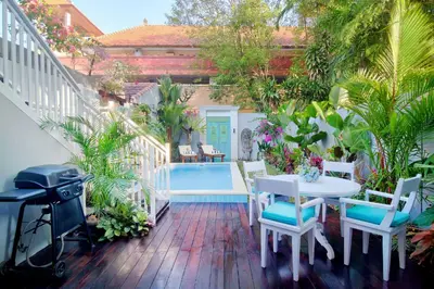a patio with a table and chairs and a pool at Selasih Beach House in Seminyak