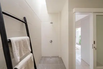 a bathroom with a walk in shower next to a glass door at The Eclipse Villas - The Luxurious 2BR Private Pool Canggu Getaway in Canggu