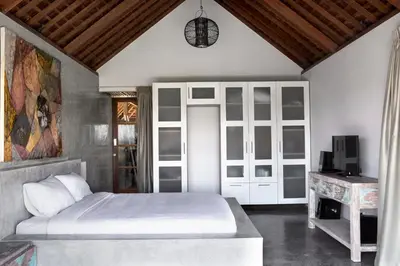 a bedroom with a white bed and a television at Surflodge Limasan Bali in Kerobokan
