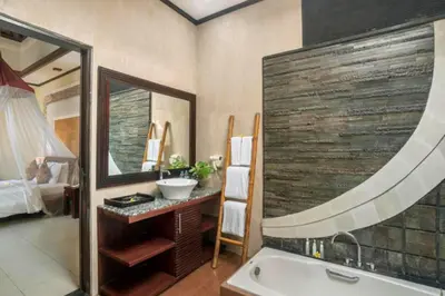 a bathroom with a tub and a sink and a mirror at Swaran 1 BR Private Pool Villa in Seminyak