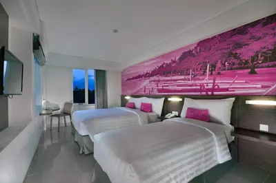 two beds in a hotel room with a painting on the wall at favehotel Sunset Seminyak in Seminyak