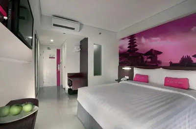 a bedroom with a large white bed with pink pillows at favehotel Sunset Seminyak in Seminyak