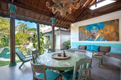 a dining room with a table and chairs and a couch at Villa Anais Seminyak in Seminyak