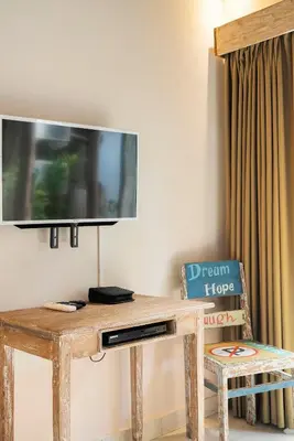 a wooden table with a tv on a wall with a chair at Villa Anais Seminyak in Seminyak