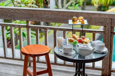 a tray of breakfast food on a table on a balcony at Sunrise Suite Seminyak by ARM Hospitality in Kerobokan