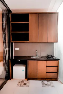 a kitchen with a sink and wooden cabinets at Sunrise Suite Seminyak by ARM Hospitality in Kerobokan