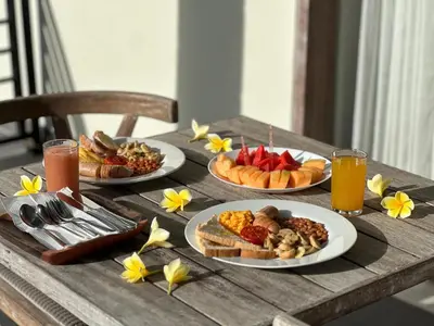 a wooden table with plates of food and drinks at Kings Villas Sanur by Moria in Denpasar